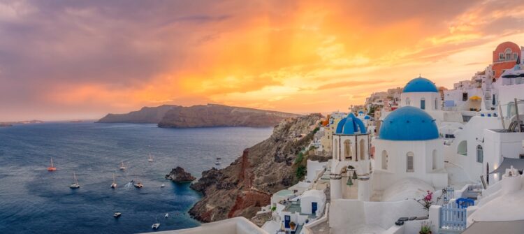 Oia town on Santorini island, Greece. Traditional famous houses and churches with blue domes over the Caldera Aegean sea
