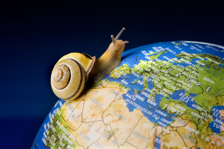 "Slow travel concept with a live snail exploring a detailed globe focused on Europe against a vibrant blue background, symbolizing eco-friendly tourism and the joy of savoring each destination."