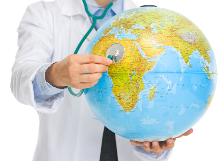 Alt text: "Travel healthcare concept with a medical professional wearing a lab coat and using a stethoscope on a colorful globe, symbolizing global health and well-being for travelers."