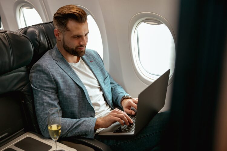 Man on airline flight working on a laptop