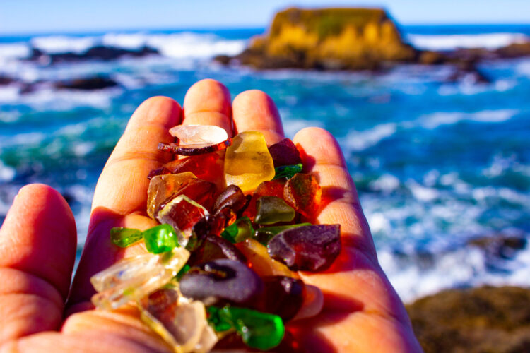 A hand holding glass shards smooth by the ocean's power