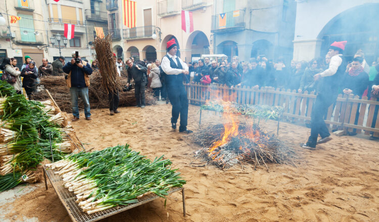Men in traditional peasant dress cooking calçots on bonfire Shutterstock Contributor BearFotos