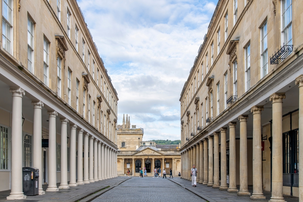 Bath Street with buildings with typical Georgian architecture and columns and entrance to Roman Baths at end of street