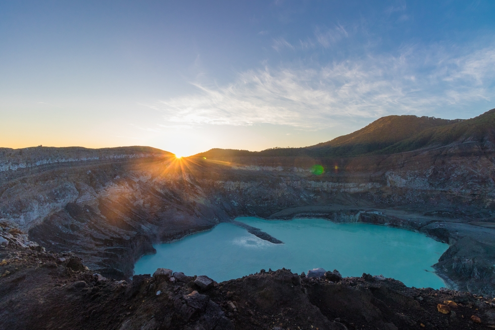 Crater of the Poas volcano at sunrise surrounded by volcanic rocks in the Poas Volcano National Park