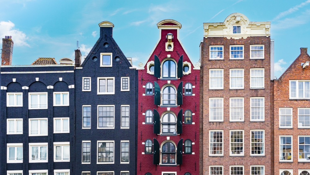 Dancing houses of Amsterdam close-up against the blue sky. Damrak Canal Houses in Amsterdam.