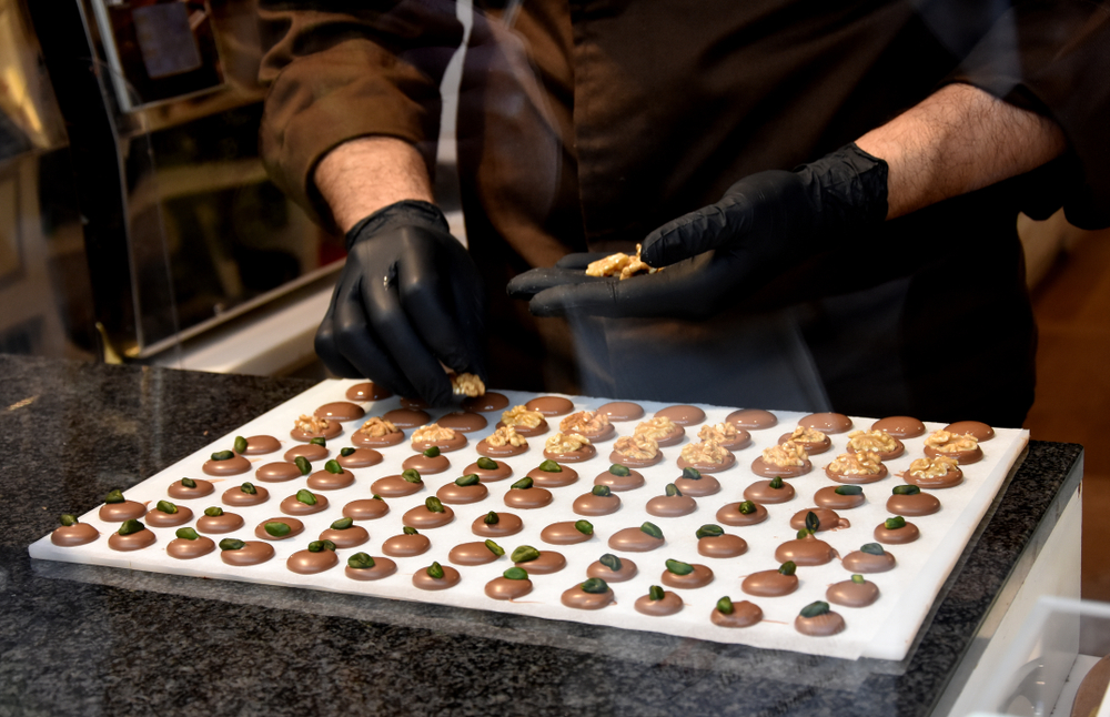 chocolate chef decorating Belgian pralines or chocolates with nuts, Brussels